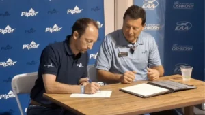 Jérémy Caussade, Président et co-fondateur d'AURA AERO, et John Calcagno, Président et CEO de Piper Aircraft, signent un protocole d'accord à EAA AirVenture Oshkosh 2026. Copyright AURA AERO