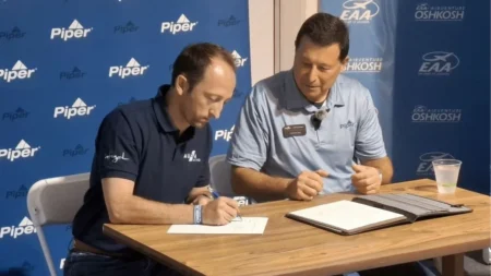 Jérémy Caussade, Président et co-fondateur d'AURA AERO, et John Calcagno, Président et CEO de Piper Aircraft, signent un protocole d'accord à EAA AirVenture Oshkosh 2026. Copyright AURA AERO